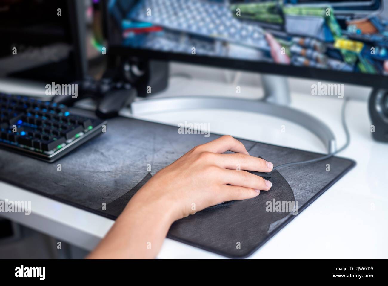 fuoco selettivo di una mano adolescente che gioca su un computer da gioco, con una tastiera nera su un grande mouse pad grigio, giochi di rete online, oltre a vi Foto Stock