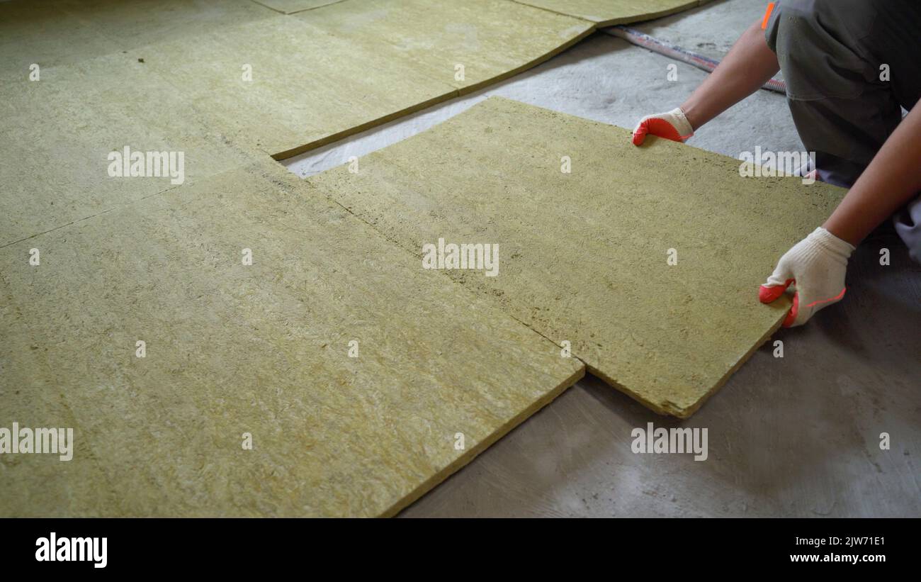 Posa di lana di vetro su un pavimento di cemento. Il costruttore isola i pavimenti della casa con lana di vetro. Foto Stock