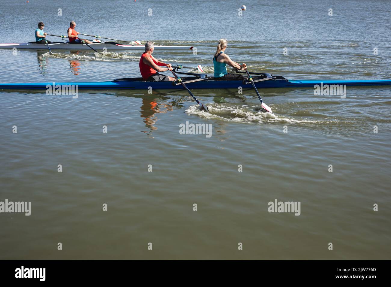 Due squadre di canottaggio caucasiche senior che si remano sulla barca sul lago Foto Stock