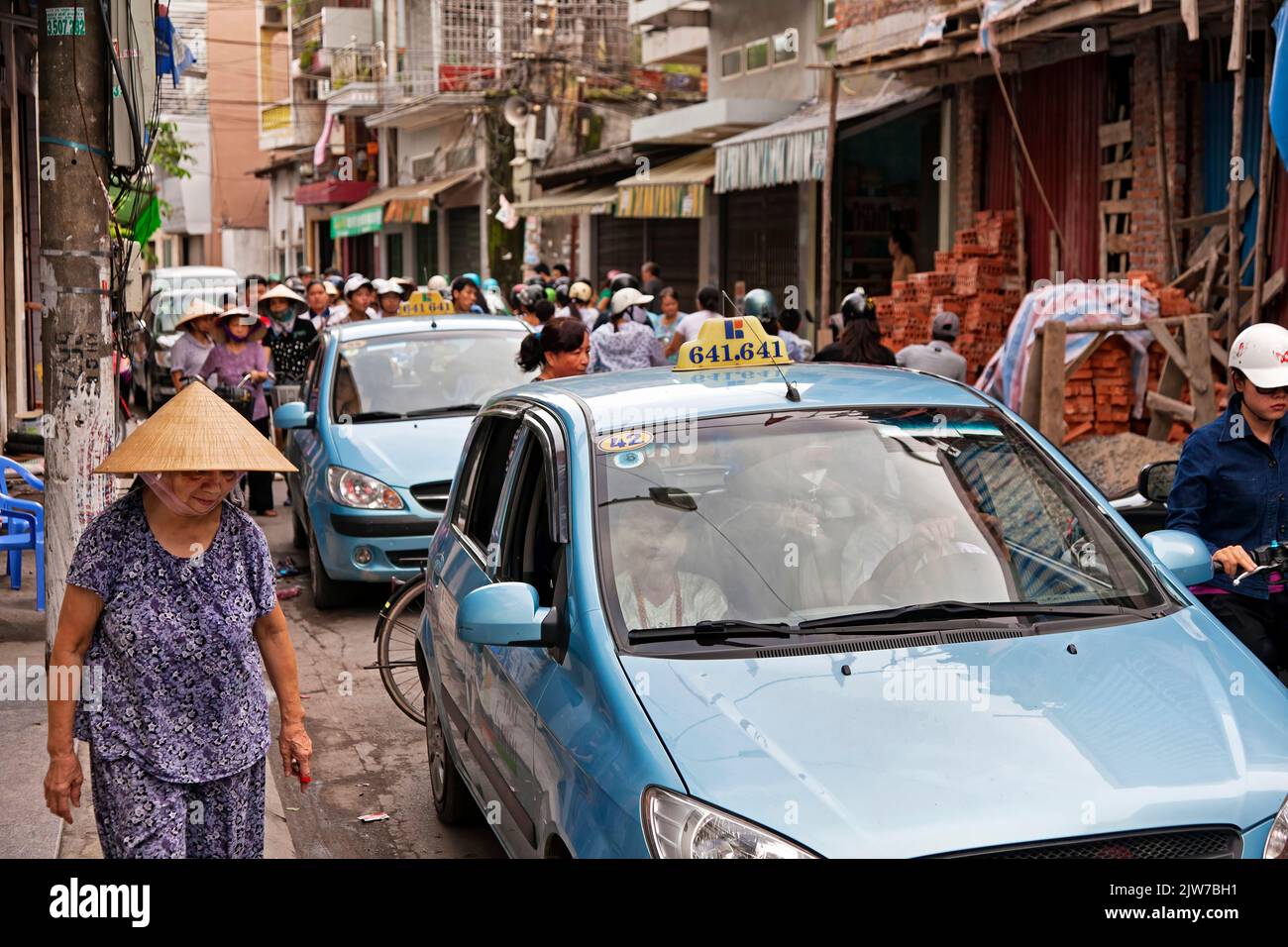Donna che indossa cappello di bambù camminando attraverso ingorghi stradali, Haiphong, Vietnam Foto Stock