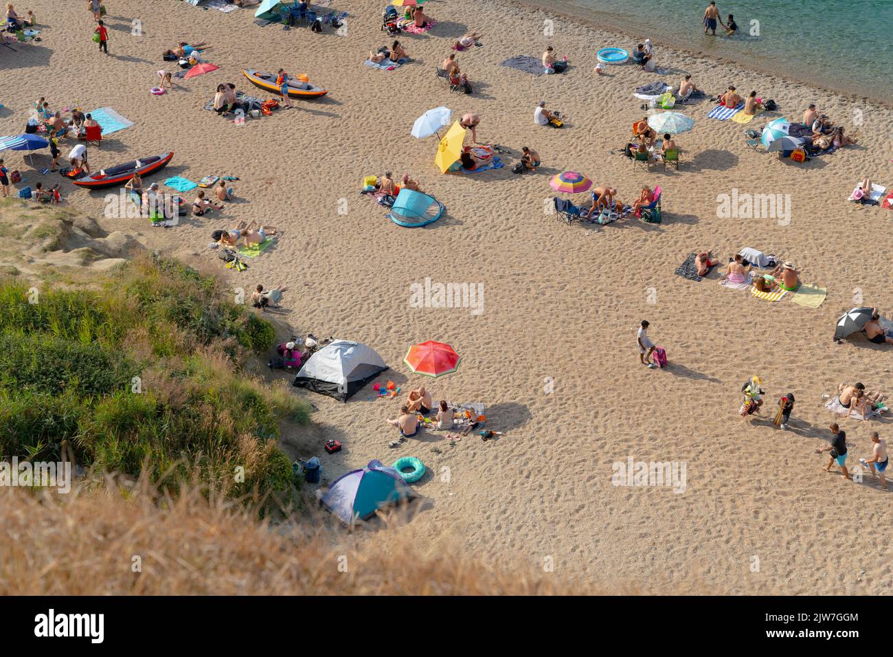 Vivace spiaggia con famiglie che si godono le vacanze estive sulla costa del Dorset Foto Stock