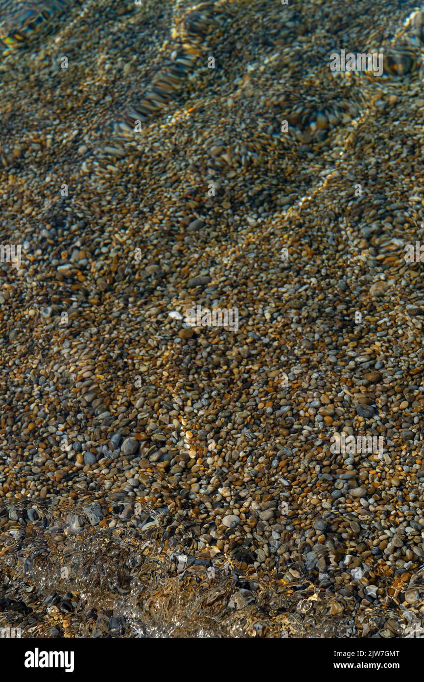 Acqua limpida che scorre su ciottoli sulla spiaggia del Dorset creando motivi e texture naturali Foto Stock