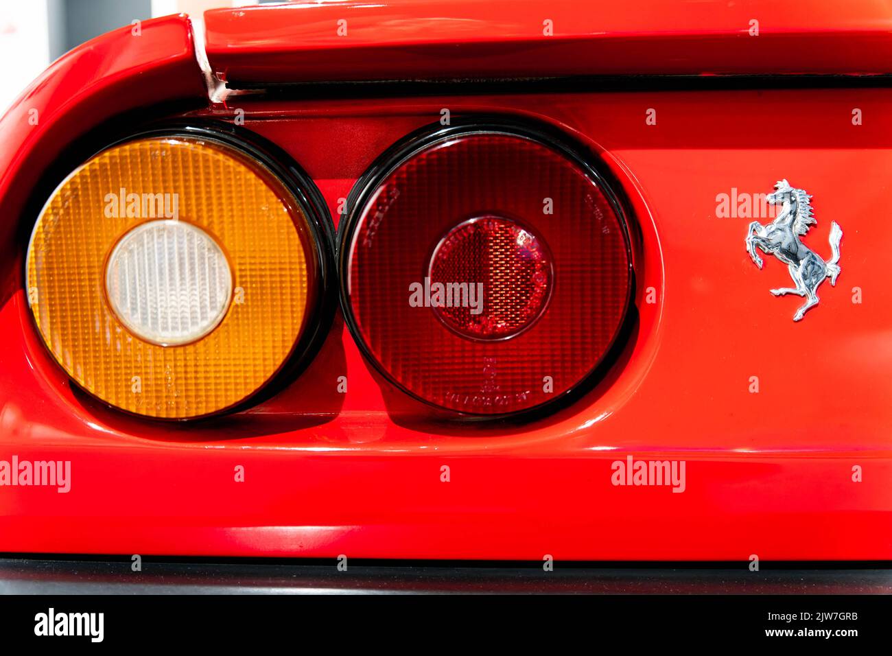 Primo piano delle luci posteriori rosse delle auto sportive Ferrari che mostrano il distintivo del cavallino e le luci di coda circolari Foto Stock