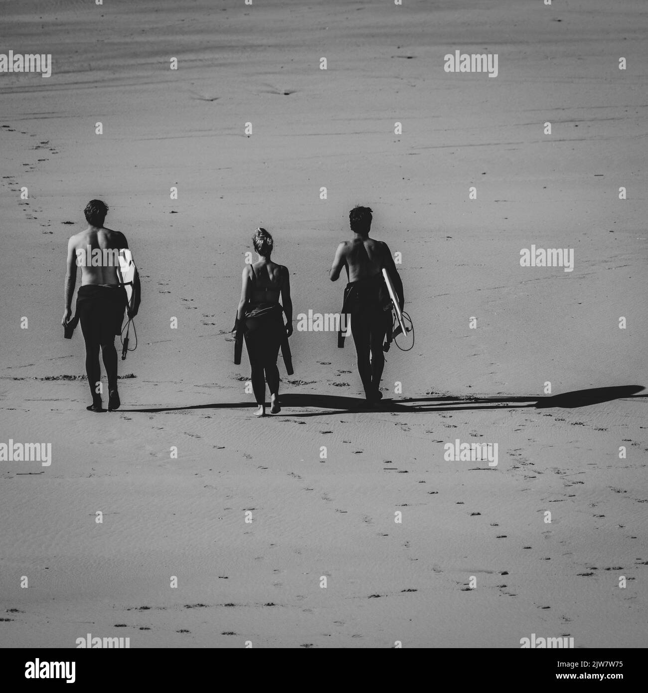 Gli uomini e le donne surfisti si godono il tempo in spiaggia a prendere le onde alla spiaggia di sabbia di Gwitian. Bianco e nero. Foto Stock
