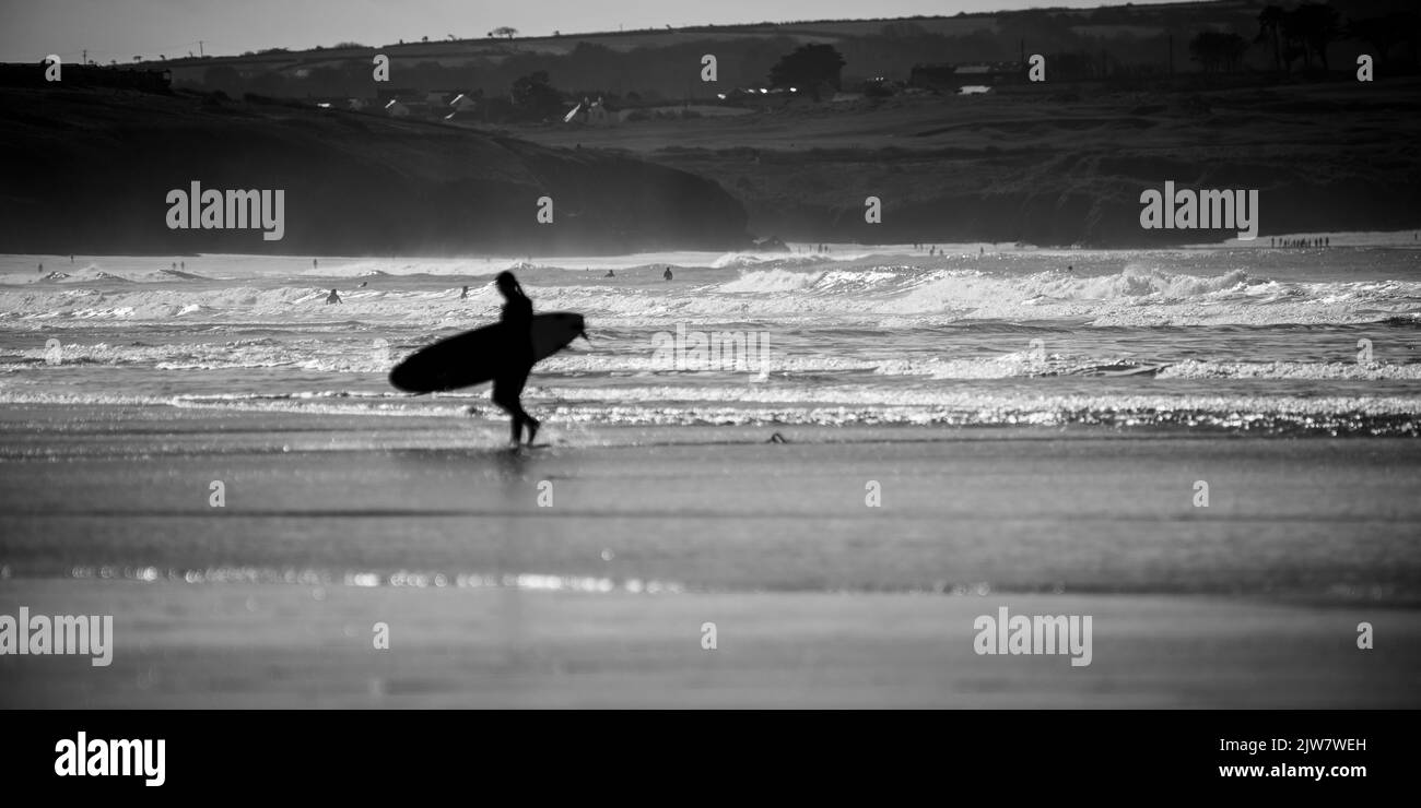 Gli uomini e le donne surfisti si godono il tempo in spiaggia a prendere le onde alla spiaggia di sabbia di Gwitian. Bianco e nero. Foto Stock
