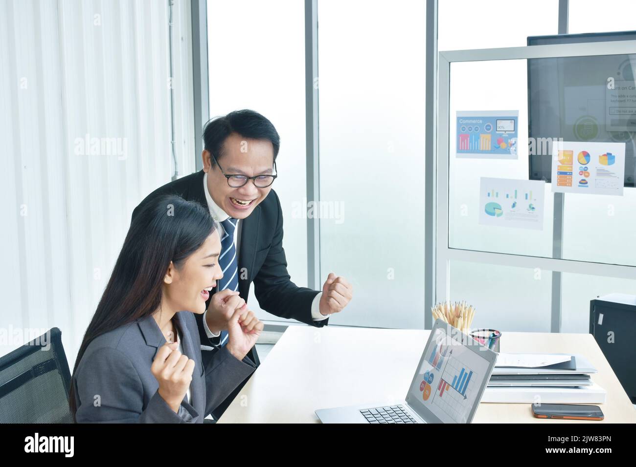 Felice uomo e donna asiatico busimess guardando lo schermo del notebook con il momento di successo in ufficio Foto Stock