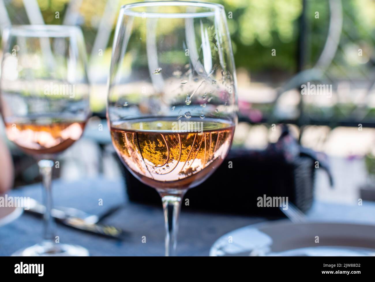 Vino rosato in bicchiere di vino primo piano con riflessi sullo sfondo sfocato del caffè estivo Foto Stock