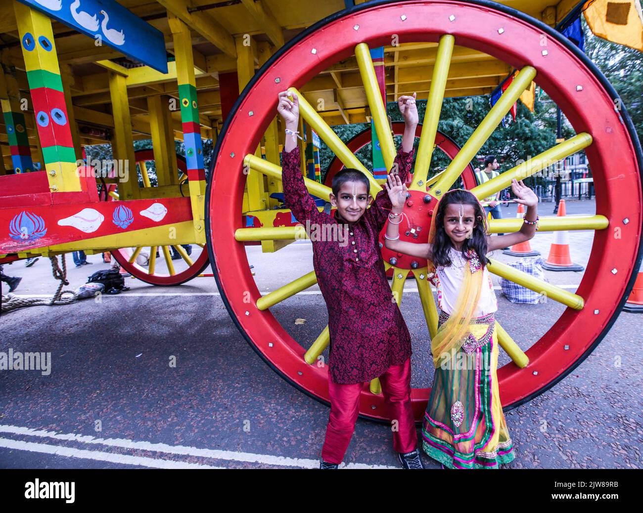 Londra UK Domenica 4th Settembre 2022 due giovani devoti di Krishna davanti ad una delle enormi ruote in legno dei carrelli, che saranno tirati a mano in una grande processione da pellegrini e devoti. In alto sui carrelli sono le divinità di Jagannatha, Balarama e Subhadra. Dopo la processione si svolge un bellissimo festival celebrativo a Trafalgar Square , con cibo vegetariano gratuito per tutti, balli e canti.Paul Quezada-Neiman/Alamy Live News Foto Stock