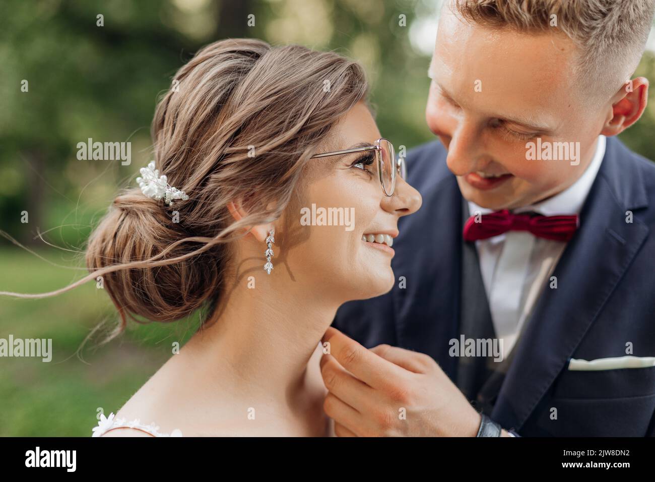 Primo piano gioioso, ridendo coppia sposata di sposo, sposa in bicchieri durante la celebrazione di nozze che si toccano nel parco Foto Stock