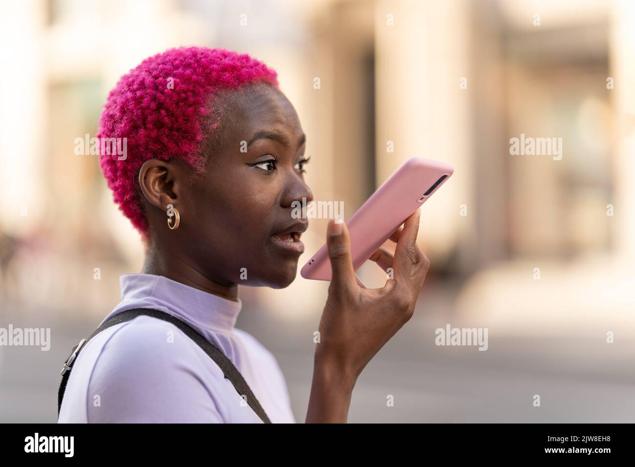 Giovane donna africana che invia un messaggio vocale con il cellulare Foto Stock