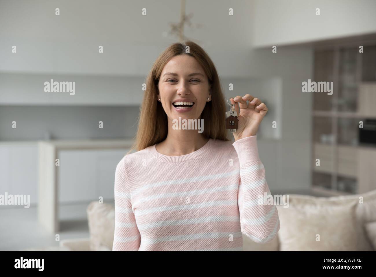 Allegra donna proprietaria di una casa che tiene la chiave del nuovo appartamento Foto Stock