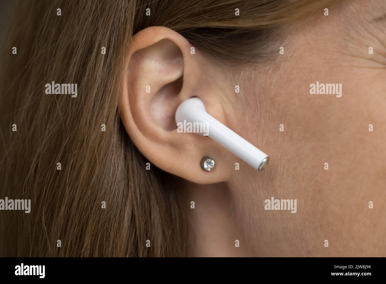 Oggetto auricolare wireless in primo piano sull'orecchio femminile Foto Stock
