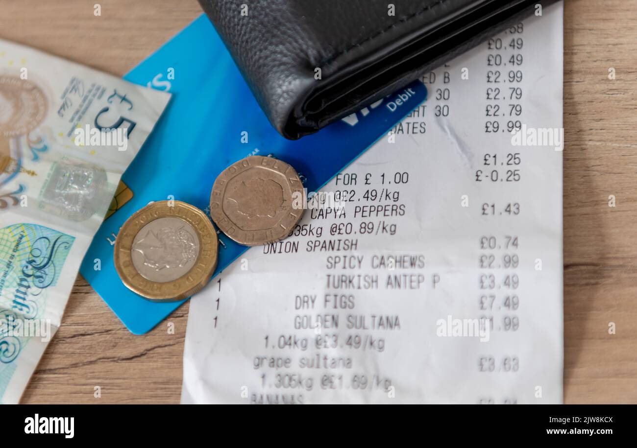 Una ricevuta, una borsa, una carta di credito e denaro contante per lo shopping su un tavolo. Costo del concetto di vita. Foto Stock