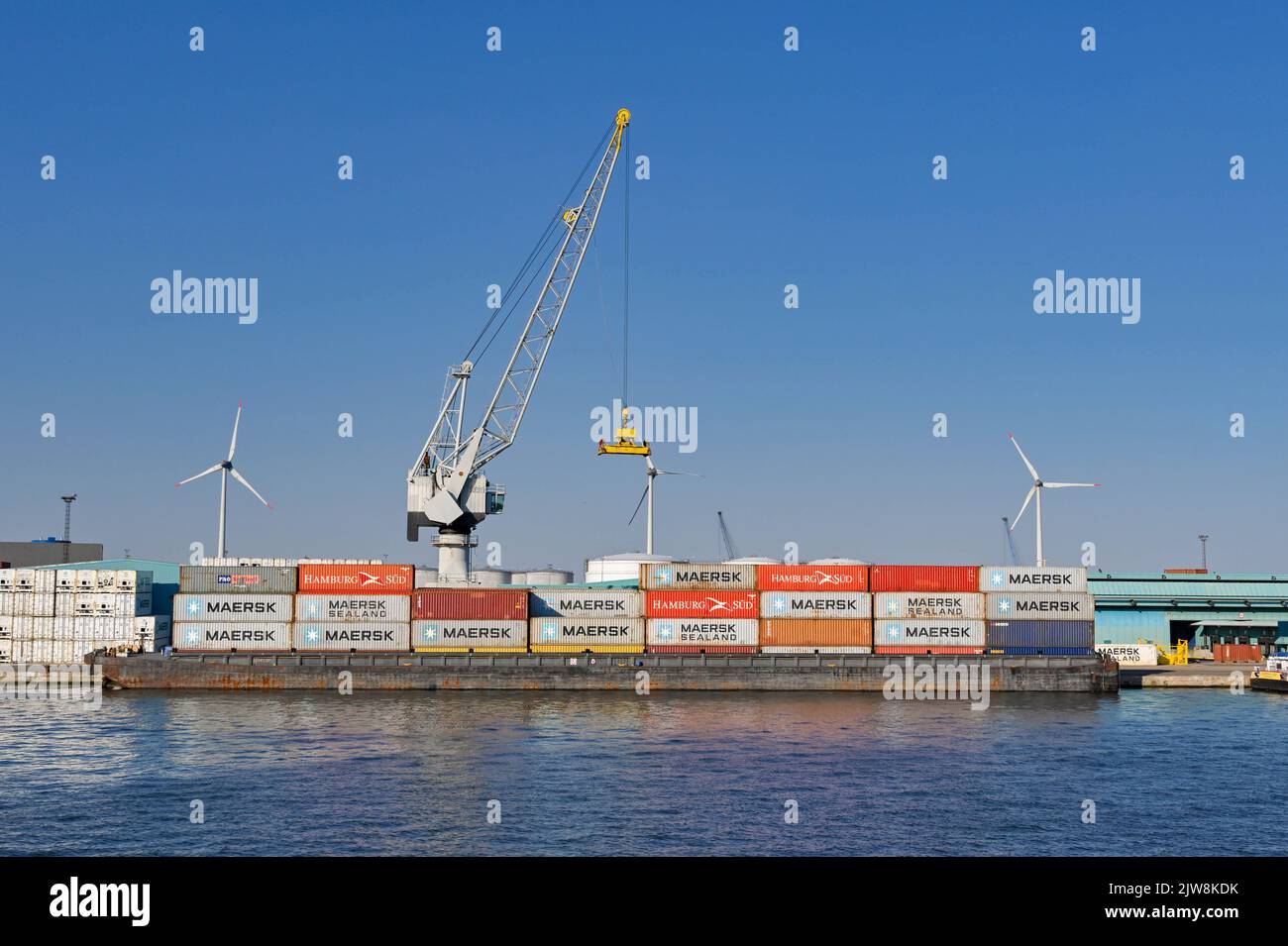 Anversa, Belgio - Agosto 2022: Gru che scarica i container da una chiatta industriale nelle banchine della città Foto Stock