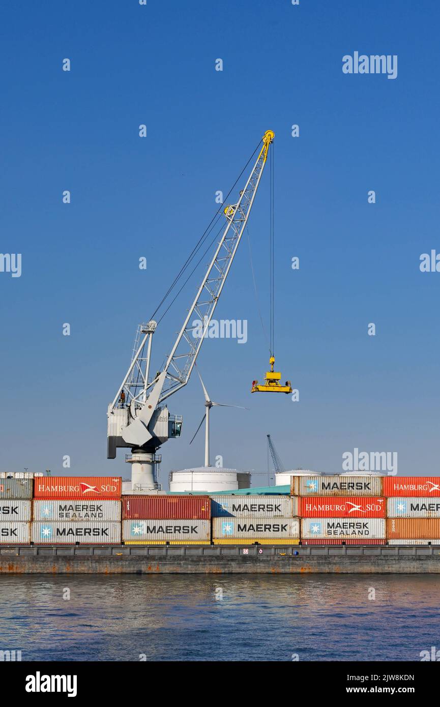 Anversa, Belgio - Agosto 2022: Gru che scarica i container da una chiatta industriale nelle banchine della città Foto Stock