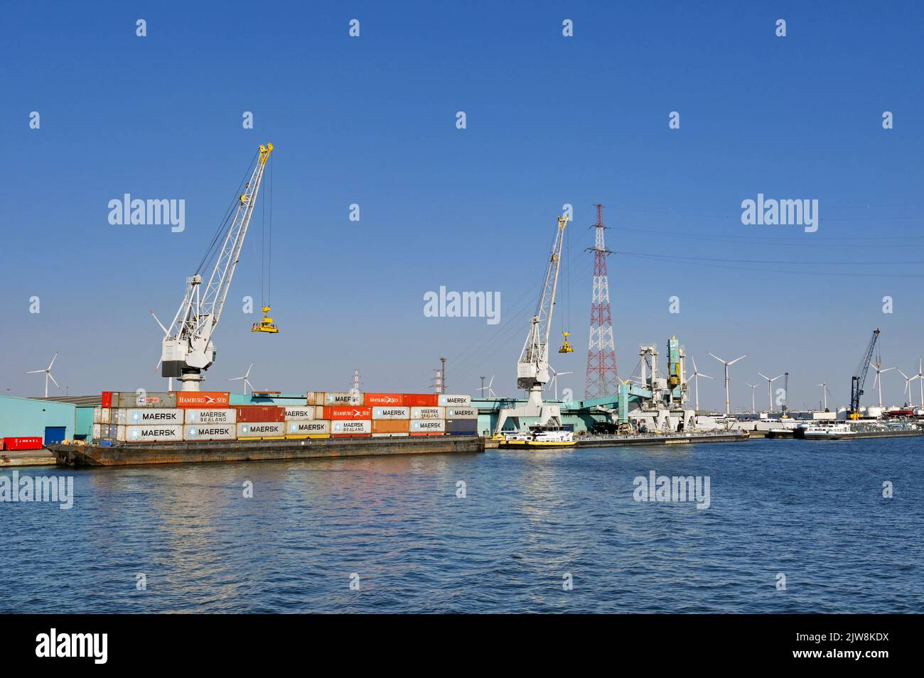 Anversa, Belgio - Agosto 2022: Vista grandangolare delle gru che scaricano i container da una chiatta industriale nelle banchine della città Foto Stock