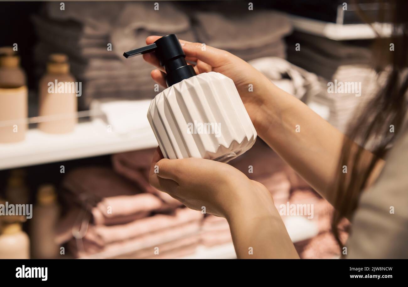 Primo piano, un dispenser per sapone liquido in mani femminili nel negozio. Foto Stock