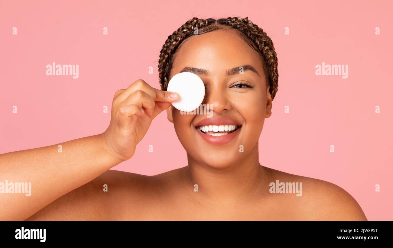 African Lady Covering Eye con imbottitura in cotone su sfondo rosa Foto Stock