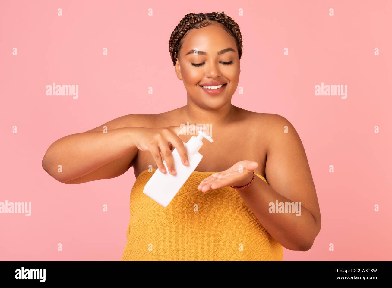 Donna nera applicazione mani idratante flacone dispenser di supporto, sfondo giallo Foto Stock