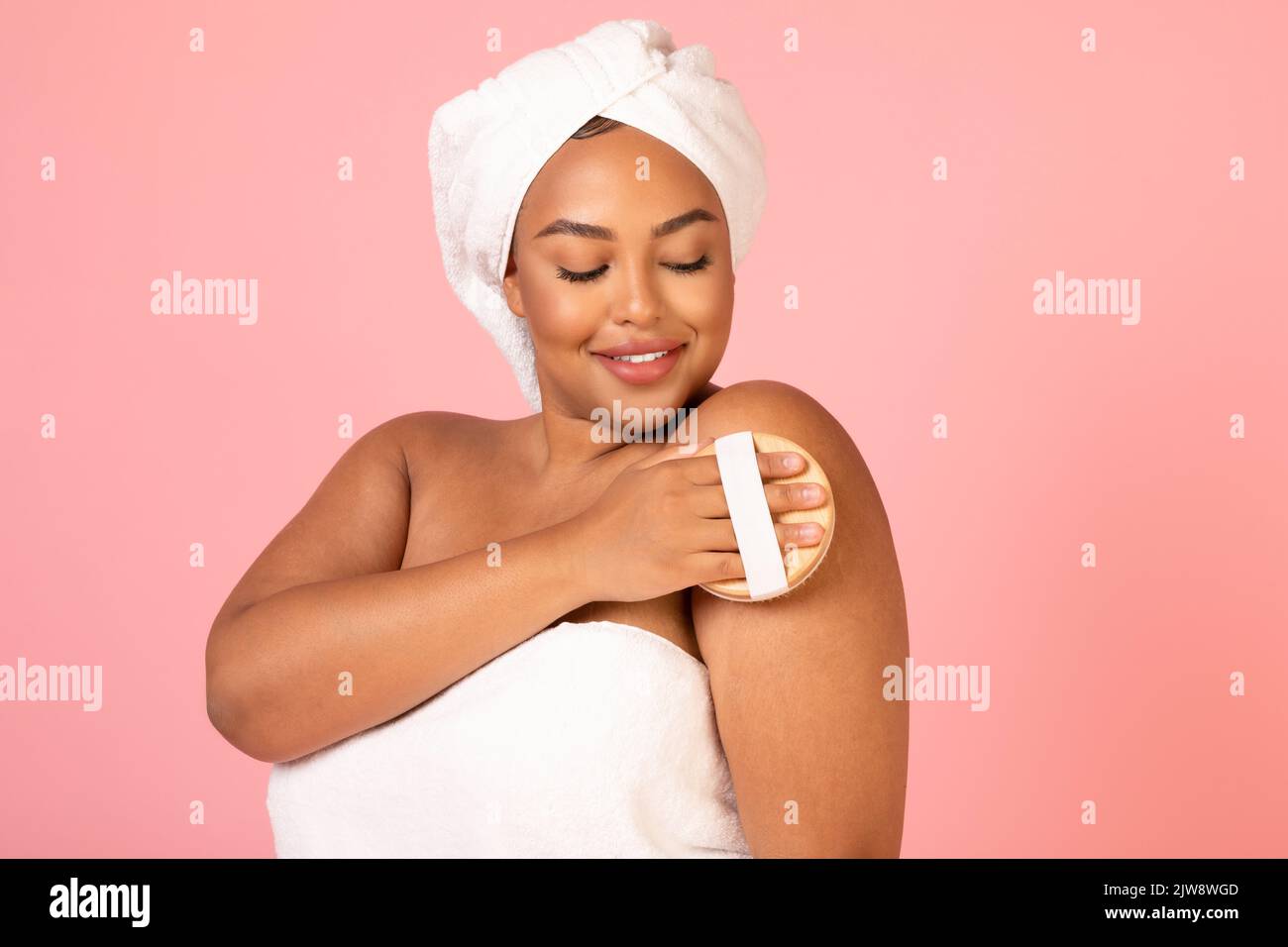 Corpo massaggiante Africano Lady con spazzola a secco su sfondo rosa Foto Stock
