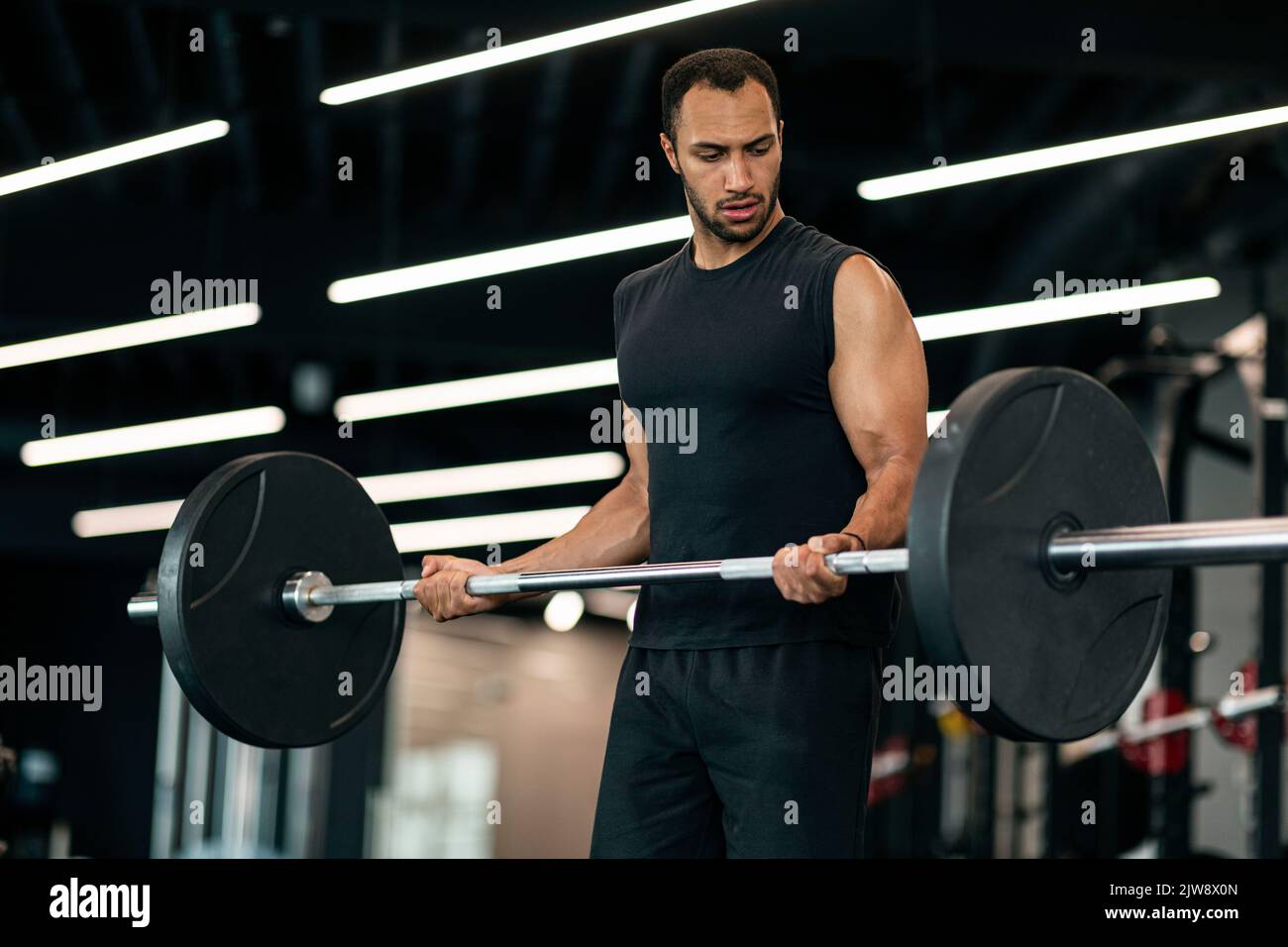 Bell'atleta nero maschio esercizio con Barbell pesante al moderno interno palestra Foto Stock