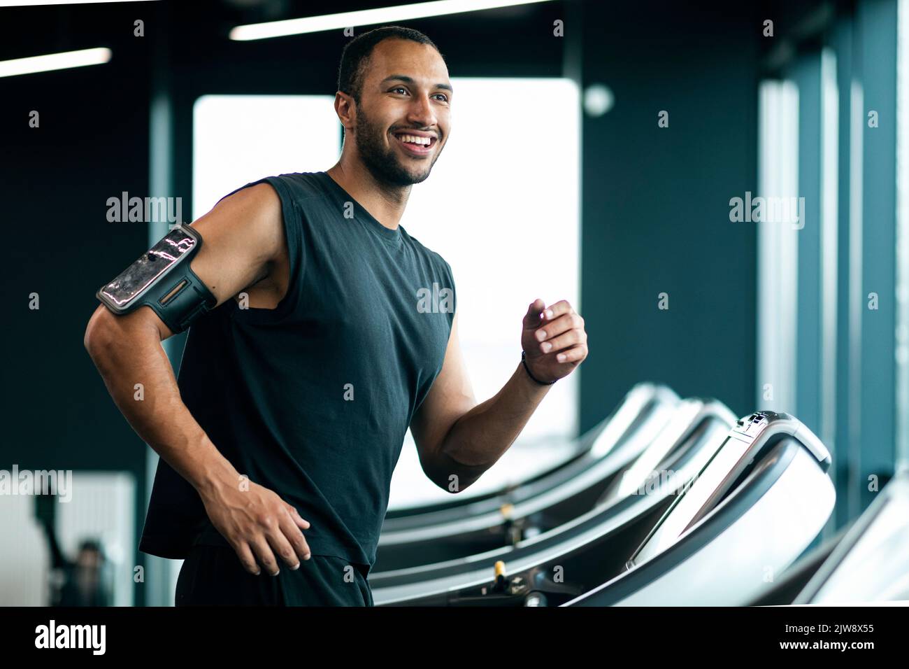 Buon giovane atleta nero maschio jogging sul tapis roulant alla palestra Foto Stock