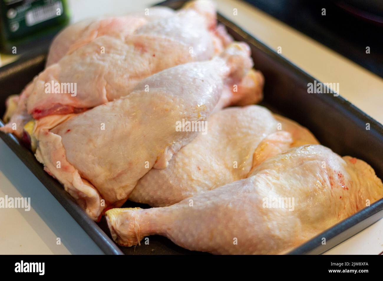 Vista ad angolo alto delle cosce di pollo crude nella teglia da forno sopra il tavolo Foto Stock