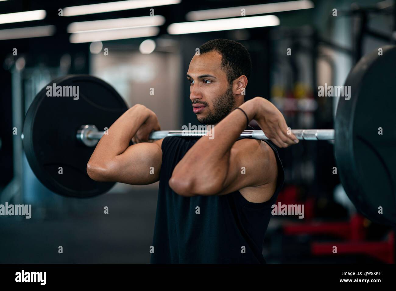 Giovane atleta nero maschile allenarsi con Heavy Barbell in palestra Foto Stock