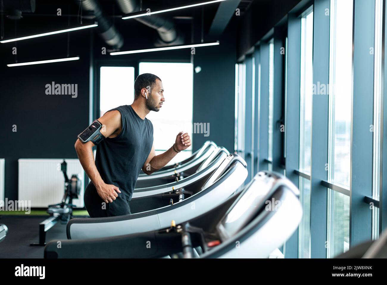 Giovane uomo nero atletico che fa jogging sul moderno tapis roulant presso la palestra Foto Stock