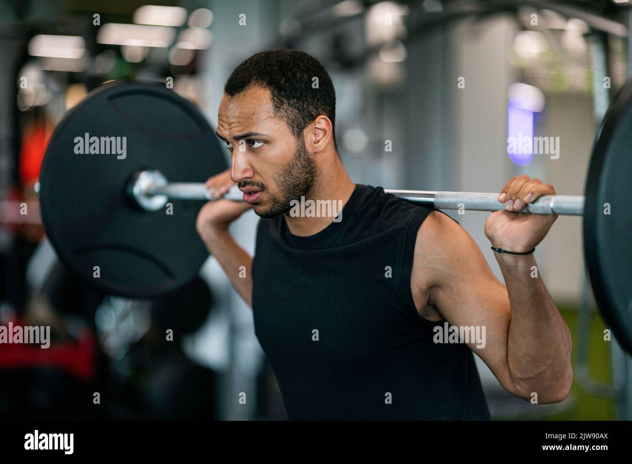 Bell'allestitore maschio nero che fa un allenamento di sollevamento pesi alla palestra Foto Stock