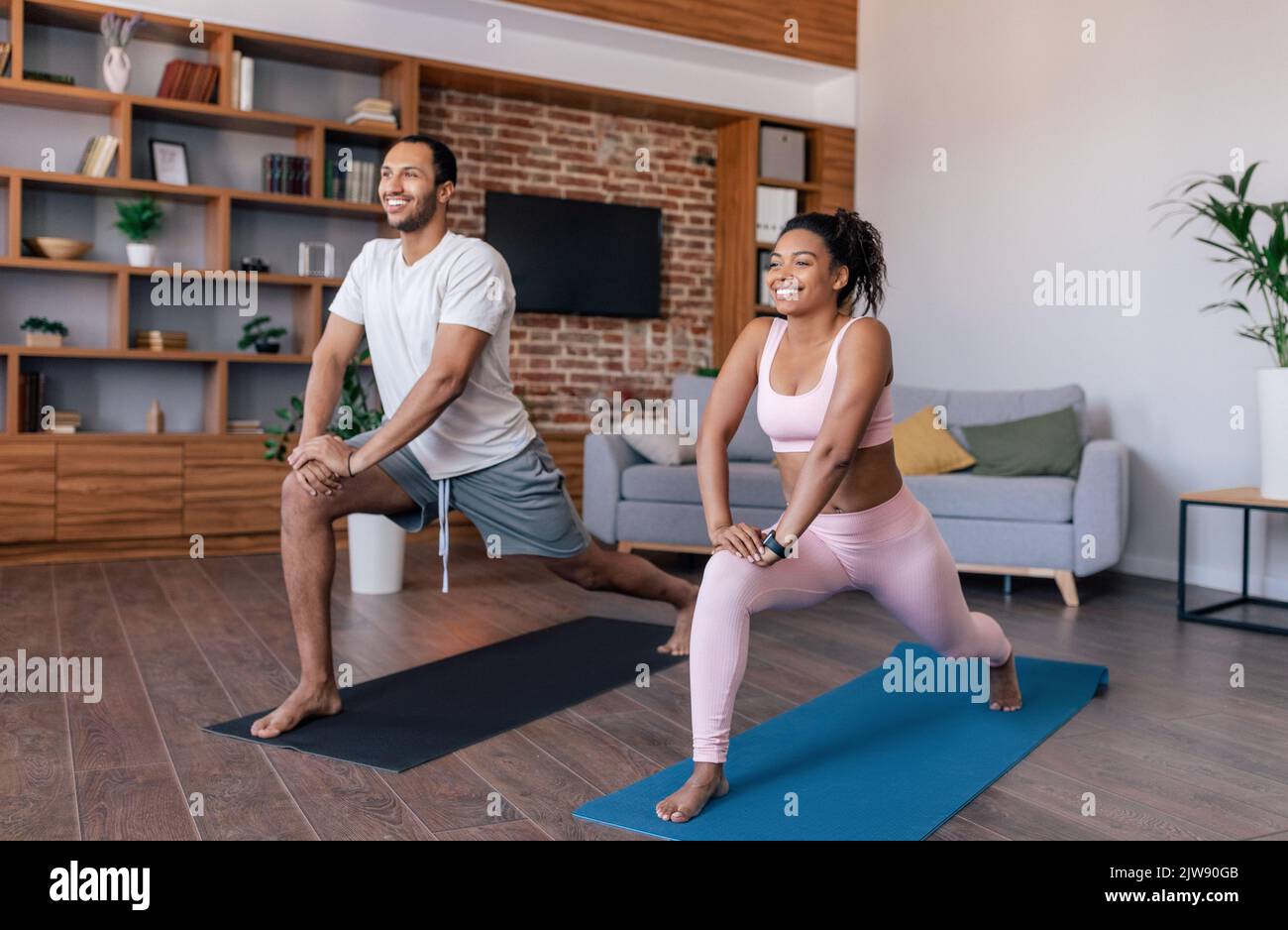 Giovani atleti di coppia afro-americani felici in abbigliamento sportivo fare esercizi o praticare yoga Foto Stock