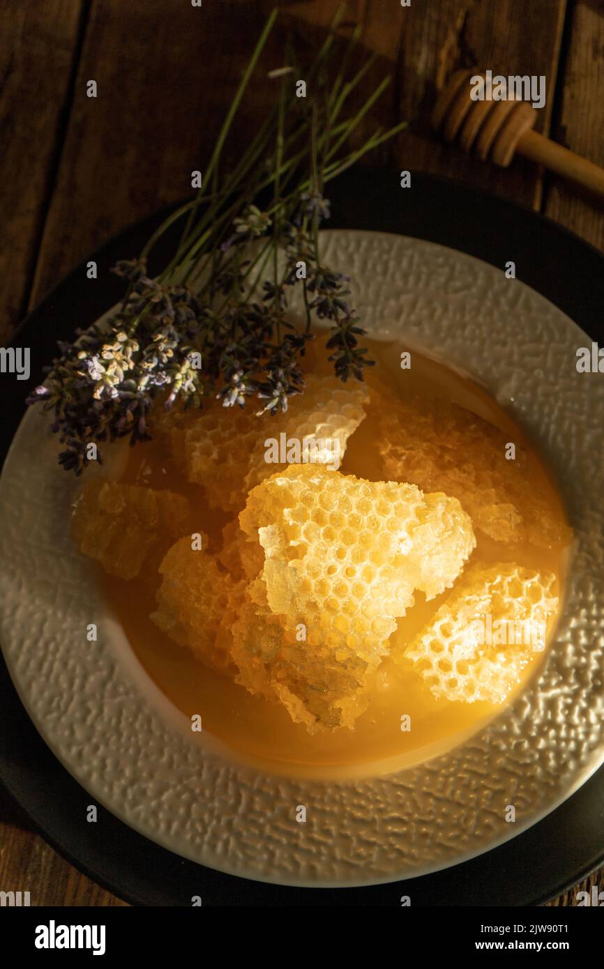 Miele e nido d'ape su un piatto bianco. Cibo dolce in una ciotola sul tavolo. Un prodotto dell'apicoltura. Fiore di lavanda. Foto Stock