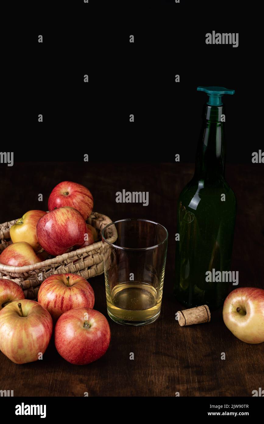 Bottiglia di sidro con tappo da versare accanto a un bicchiere di sidro e alcune mele. Foto Stock