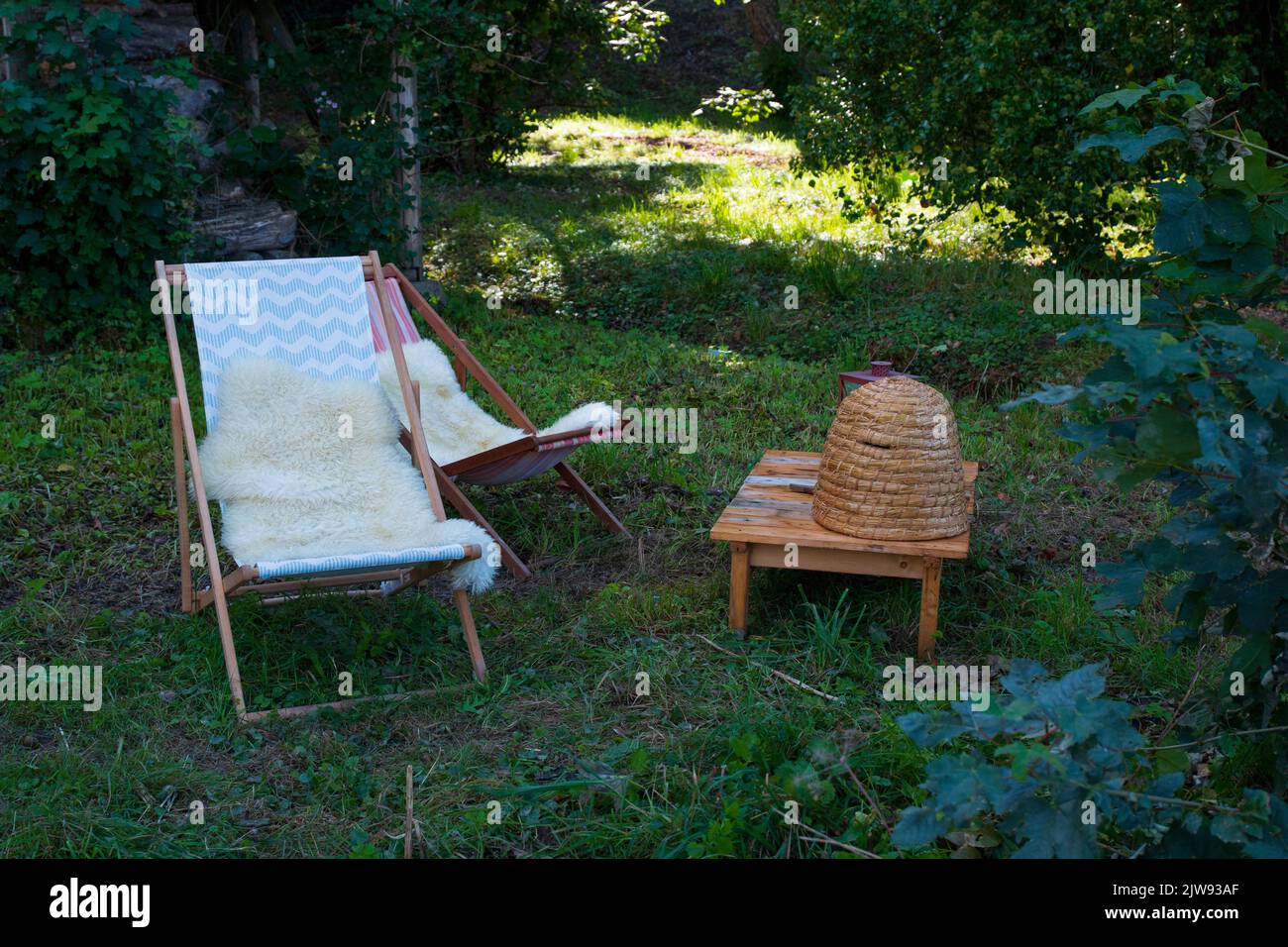 Liegestuhl aus Holz im Wald, romantisch mit Bienenkorb Deko Foto Stock