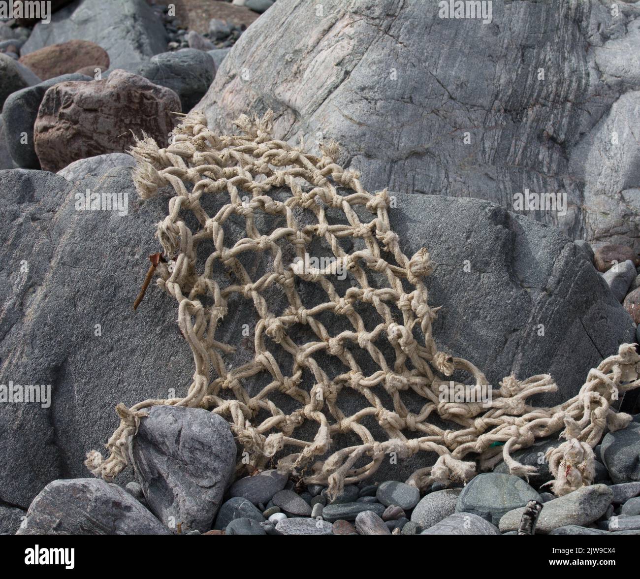 Parti di una rete lacerata si lavano come flotsam sulle rocce a Caggwith Cove, Cornovaglia. Foto Stock