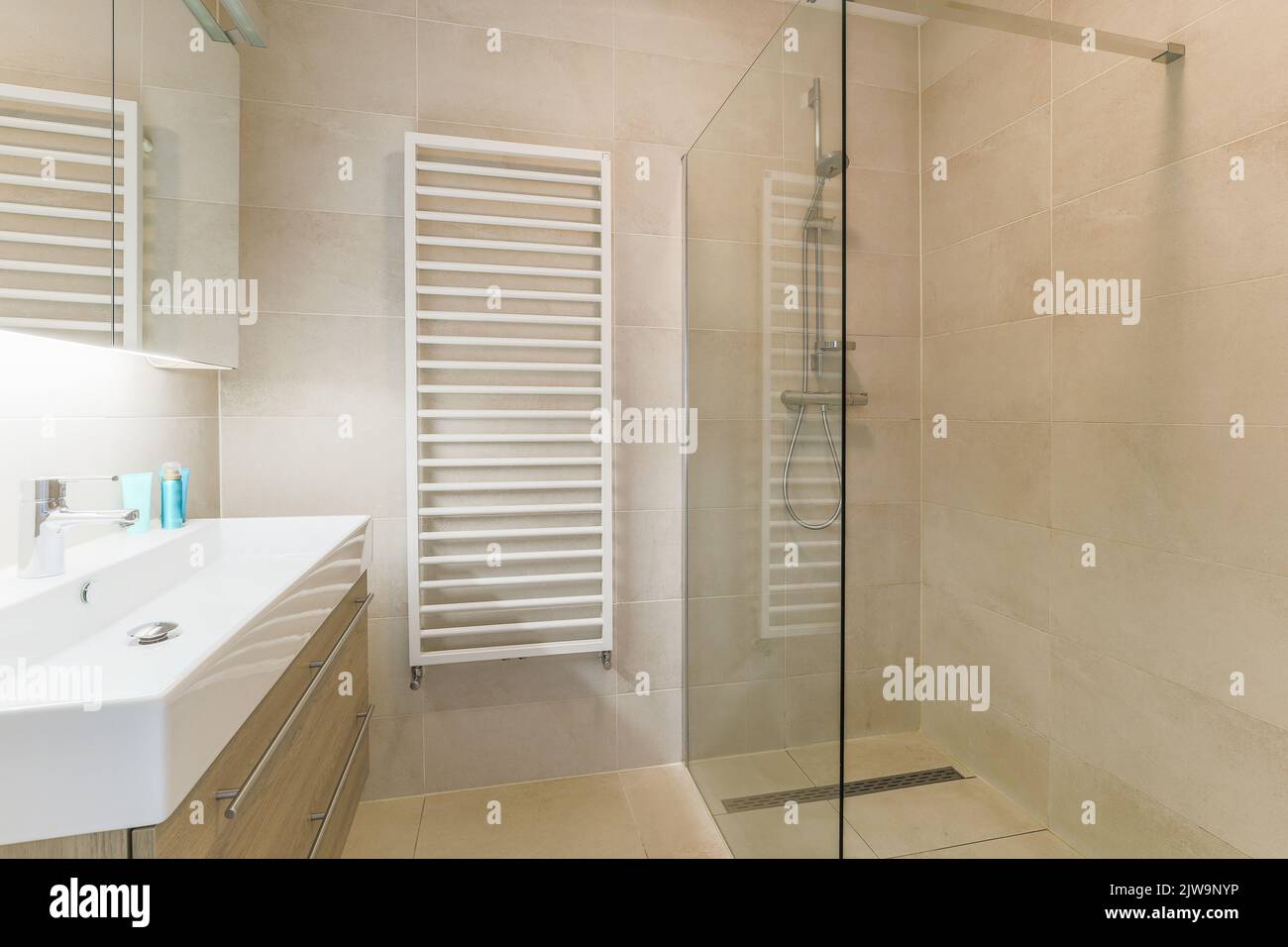 Interni di bagno contemporaneo con pareti e divisori beige scablato. Foto Stock