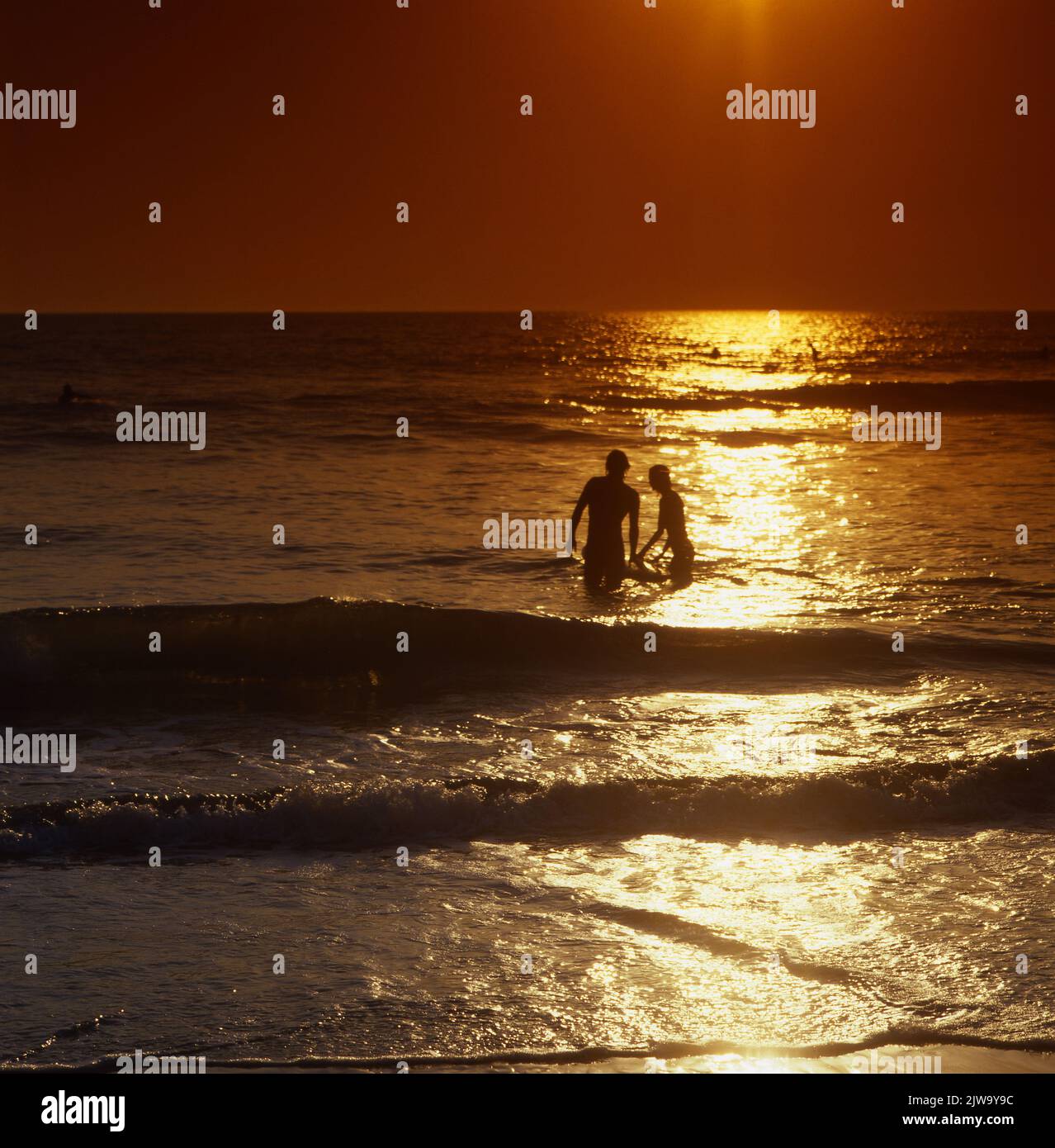 Giovane coppia prendere bagno sulla spiaggia armoniosa silhouette riflesso tramonto Foto Stock