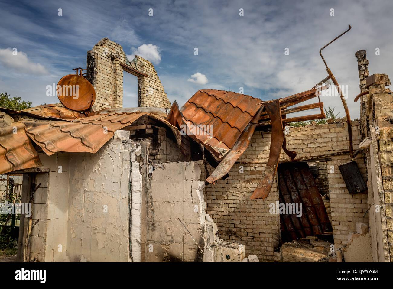 Rovine di una casa privata. Casa bruciata. Un'arrugginita parabola satellitare. Vita rovinata. Resti dell'edificio. Guerra in Ucraina. Casa bruciata. Missile colpito. Foto Stock