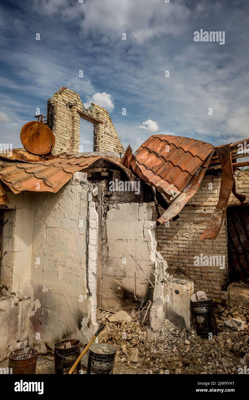 Rovine di una casa privata. Casa bruciata. Un'arrugginita parabola satellitare. Vita rovinata. Resti dell'edificio. Guerra in Ucraina. Casa bruciata. Missile colpito. Foto Stock