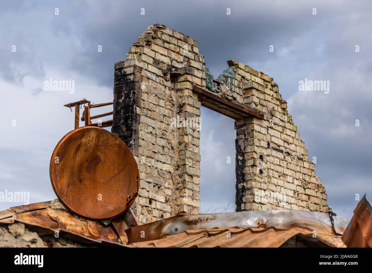 Rovine di una casa privata. Casa bruciata. Un'arrugginita parabola satellitare. Vita rovinata. Resti dell'edificio. Guerra in Ucraina. Casa bruciata. Missile colpito. Foto Stock