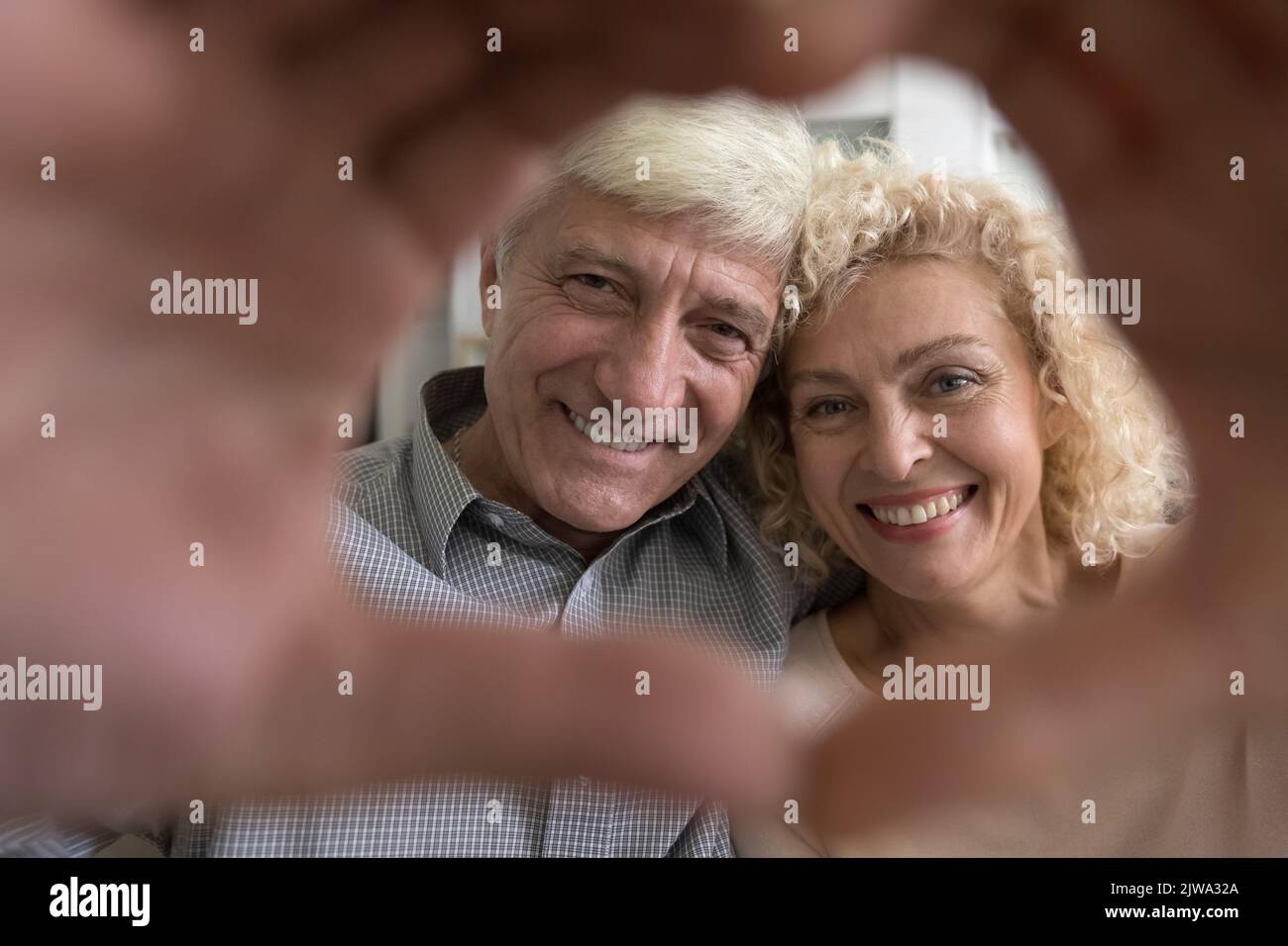 Felice ritratto di coppia amante anziano con cornice a forma di cuore a mano Foto Stock
