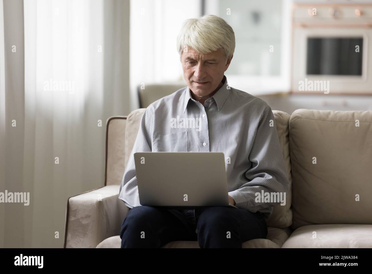 Uomo d'affari freelance maturo concentrato che lavora a casa, scrivendo sul laptop Foto Stock