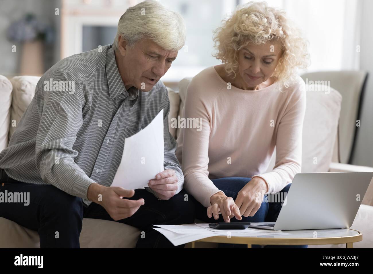 Focalizzato coppie in pensione che controllano le fatture, le fatture cartacee Foto Stock