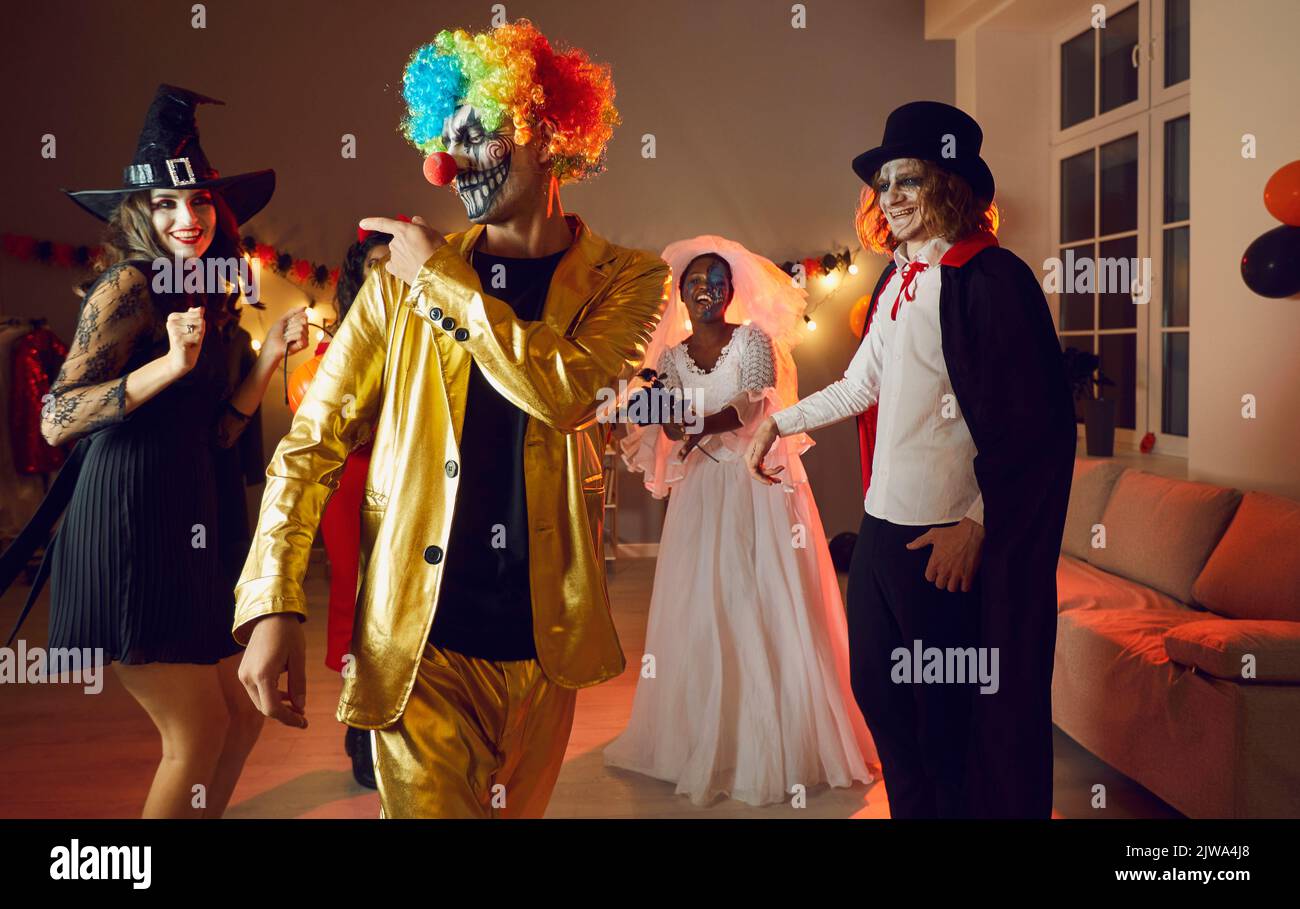 Giovane uomo allegro e fiducioso in costume da clown spoky che si diverte alla festa di Halloween. Foto Stock
