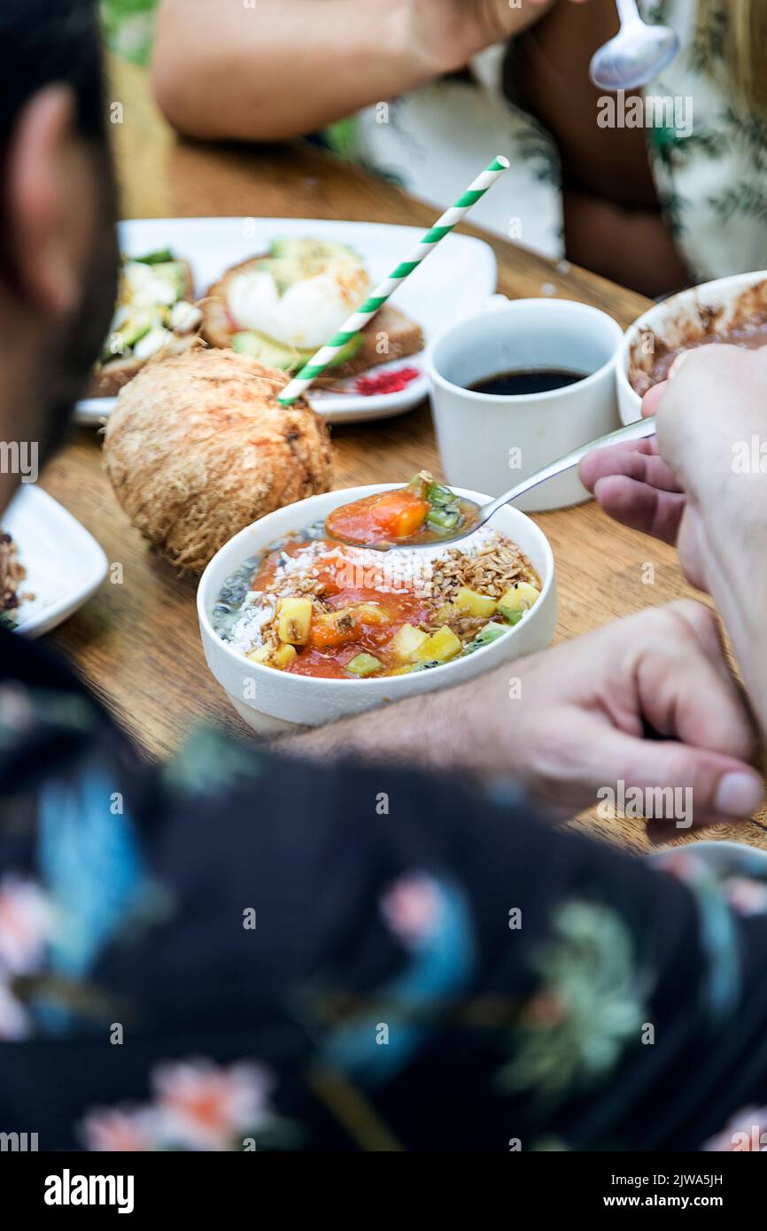 Gli amici potranno gustare una colazione vegetariana con pane tostato, uova strapazzate, cocco e avocado. Godendo la compagnia di amici e cibo. Atmosfera estiva Foto Stock