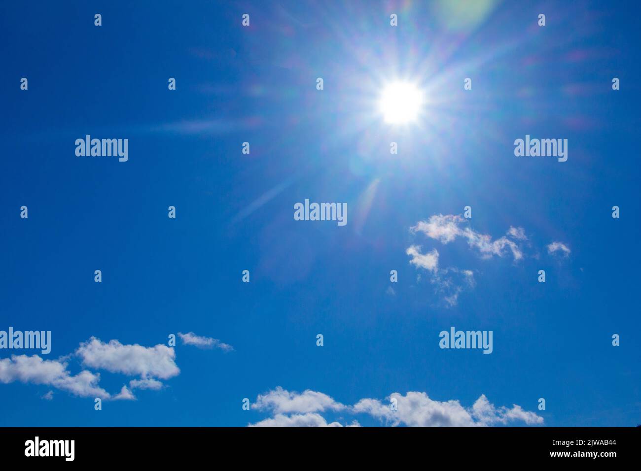 Paesaggio di un cielo estivo blu luminoso con un sole bianco e nuvole in pace. Foto Stock