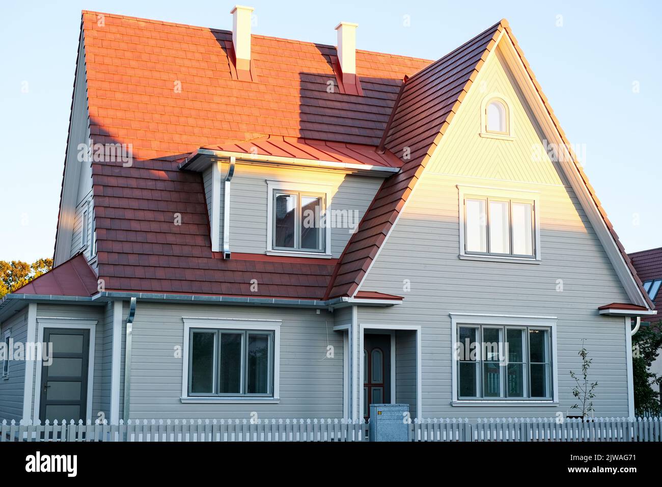 Una casa privata di due piani con tetto triangolare e un'area vicino alla casa contro un cielo blu Foto Stock