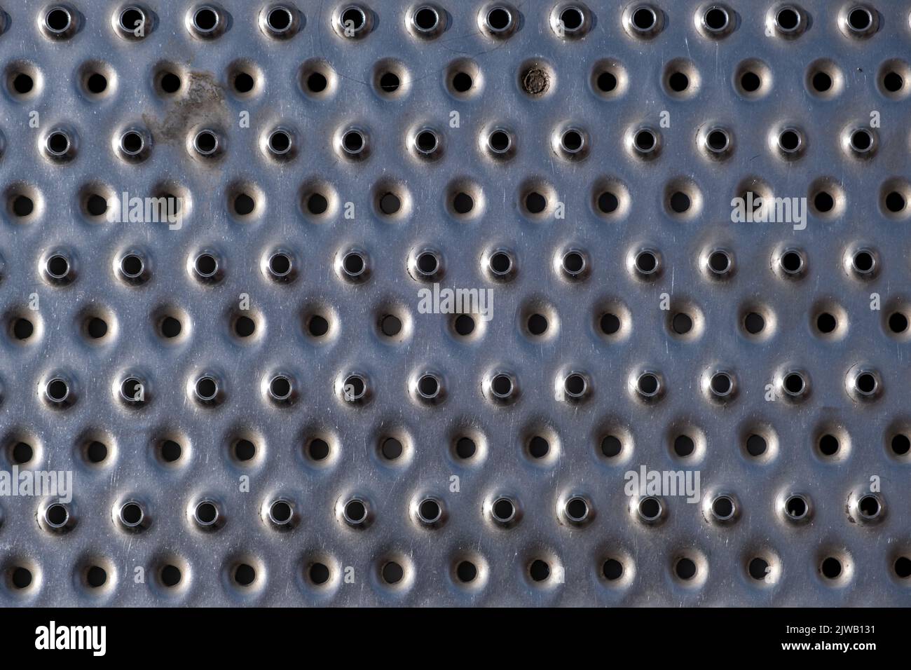 vista di una piastra in acciaio con piccoli fori rotondi punzonati Foto Stock