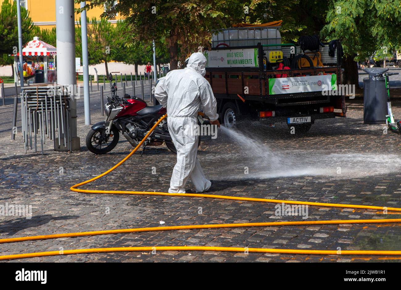 Tuta protettiva monouso bianca completa DPI pulizia stradale con tubo flessibile a Lisbona, Portogallo Foto Stock