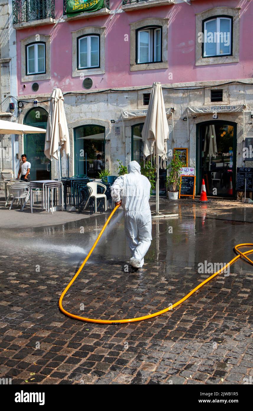 Tuta protettiva monouso bianca completa DPI pulizia stradale con tubo flessibile a Lisbona, Portogallo Foto Stock